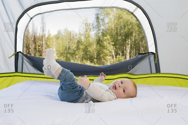 USA, Utah, Uinta National Park, Baby boy (6-11 months) lying in tent, forest in background