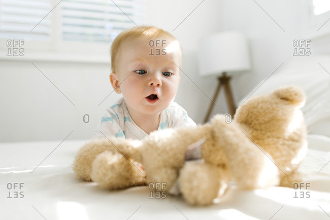 Baby boy (6-11 months) looking at teddy bear on bed