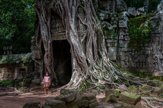 SIEM REAP, CAMBODIA - 08 July 2012; Ta Som famous back gate with tree growing out of it. Young girl sells trinkets.