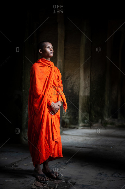 SIEM REAP, CAMBODIA - 26 April 2014: Monk looks towards the light  at north gate  of Angkor Wat.