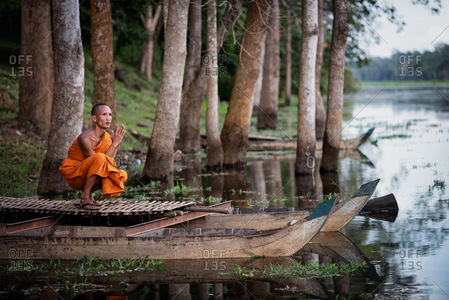 SIEM REAP, CAMBODIA - 16 AUGUST 2014: Monks prays on boat on moat at South gate of Angkor Thom.
