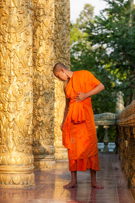 KAMPOT PROVINCE, CAMBODIA - 07 February 2012. Monk adjusts his robe before entering temple.