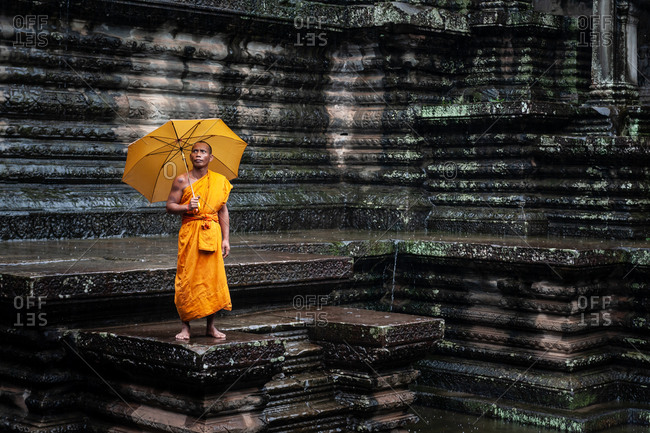 SIEM REAP, CAMBODIA - 28 September 2013: Monk braves rain in  Angkor Wat  open court yard.