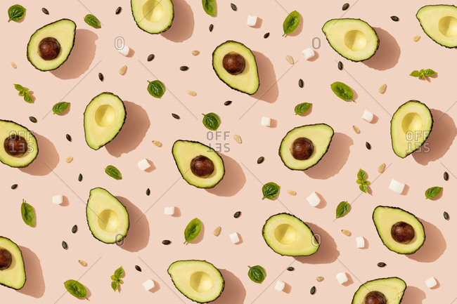 Pattern of halved avocados- pumpkin seeds- basil and pieces of cheese
