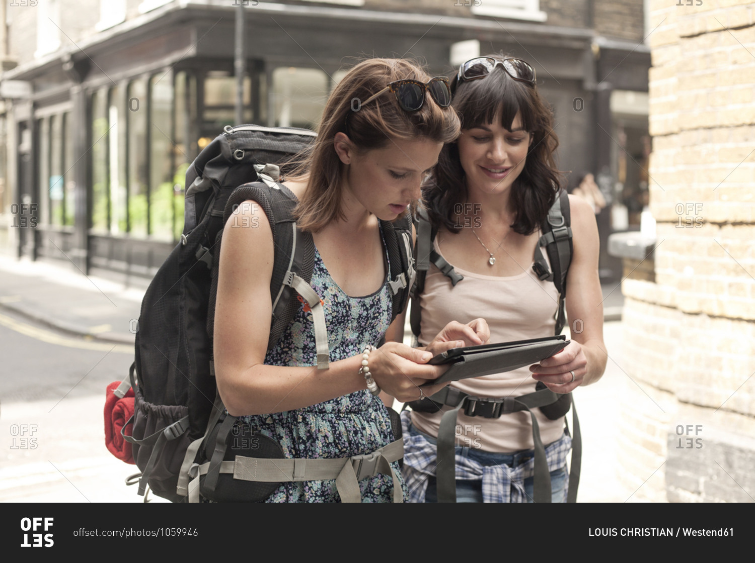 Female backpackers using digital tablet for guidance map while exploring city