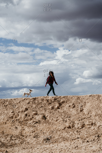Spain- Navarre- Young woman hiking with dog in Bardenas Reales