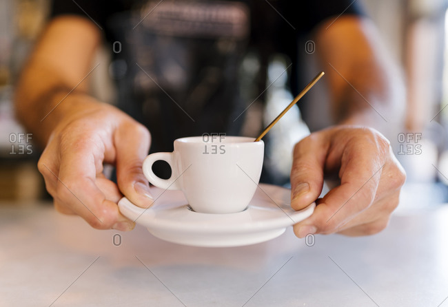 Male barista serving coffee at counter in cafe