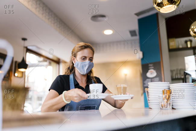 Female barista serving coffee at counter in cafe