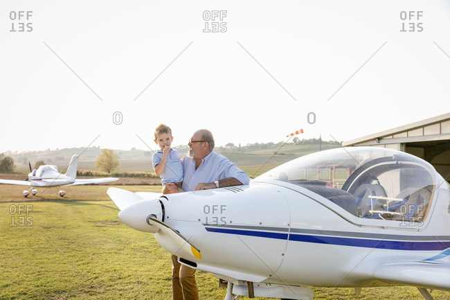 Grandfather picking up grandson while standing at airfield