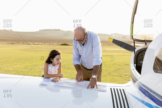 Grandfather and little girl concentrating while looking at map on sunny day