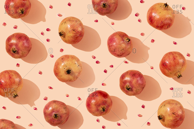 Ripe pomegranates with seeds arranged on beige background