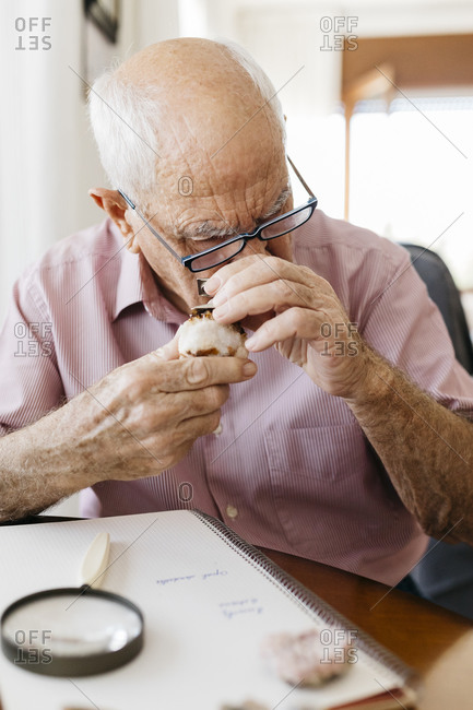 Senior man looking through loupe at mineral