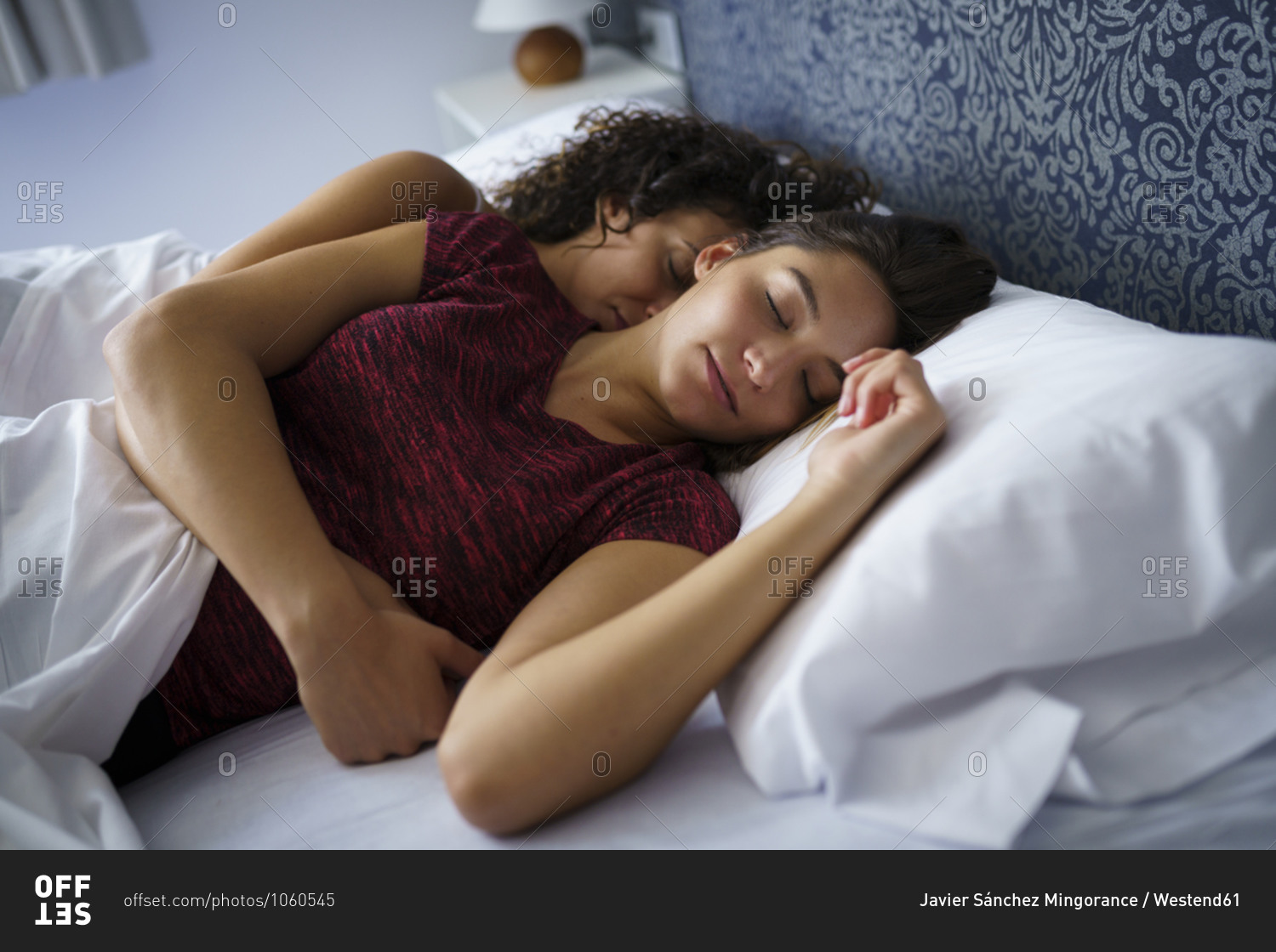 Beautiful lesbian couple sleeping on bed at home stock photo - OFFSET