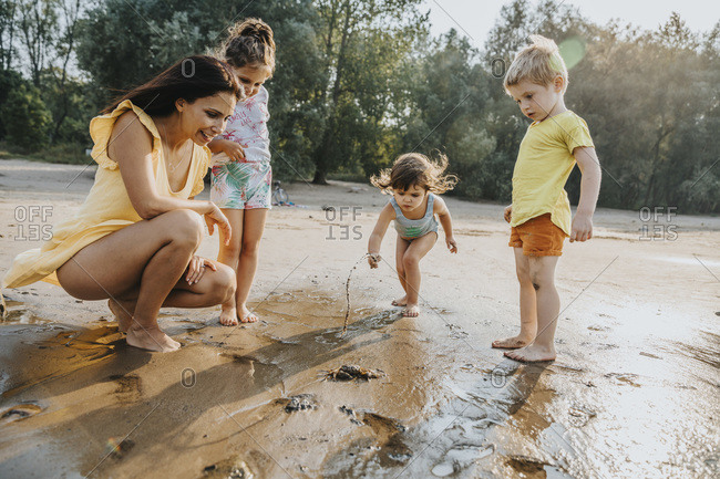 Mature woman and children discovering crab at beach