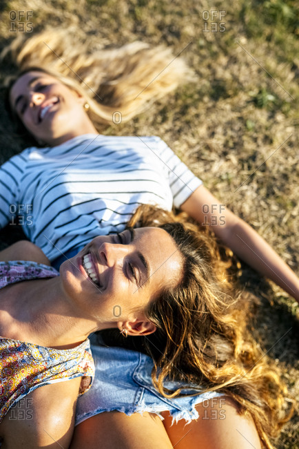 Cheerful young women relaxing on field during sunny day