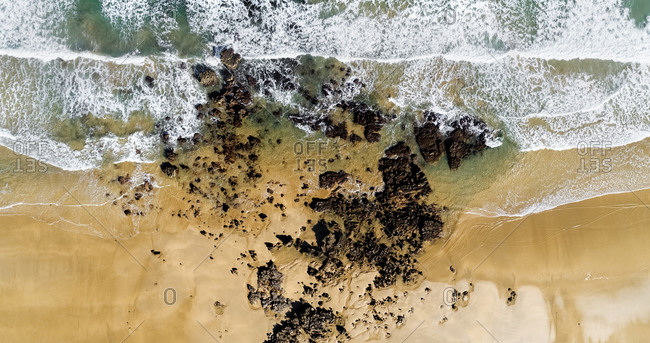 Aerial view of rocks on sandy coastal beach