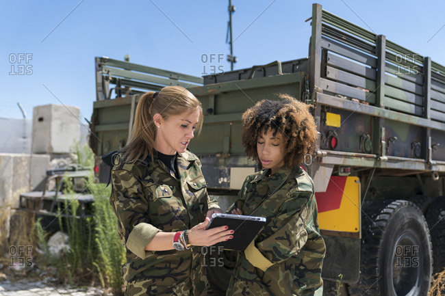 Multi-ethnic female army soldiers discussing over digital tablet at military base on sunny day