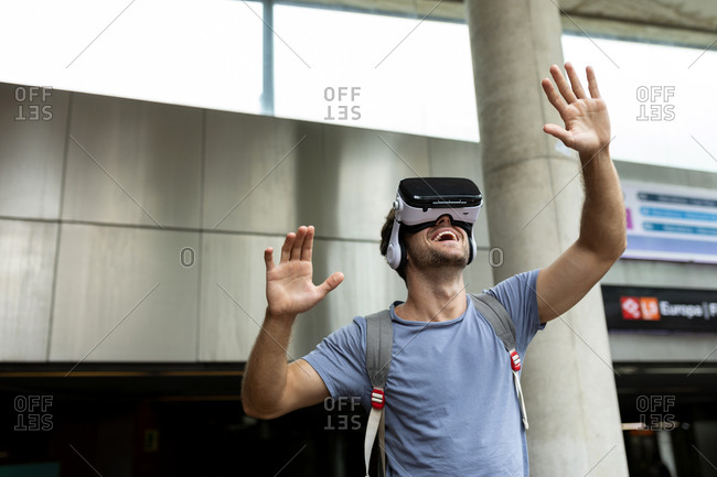 Smiling young male commuter enjoying virtual reality headset at subway station