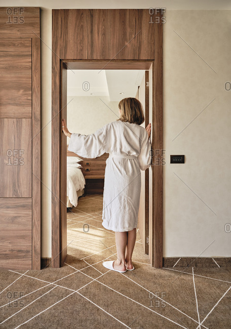 Senior woman in bathrobe standing at hotel room doorway