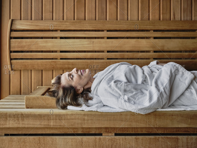 Senior woman reclining on wooden sauna at health spa