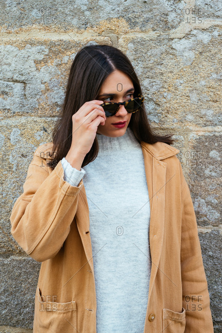 Beautiful young woman posing over a wall wearing sunglasses