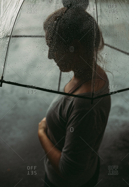 Woman holding an umbrella and looking down on a rainy day.