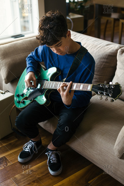 Teen boy practicing electric guitar at home