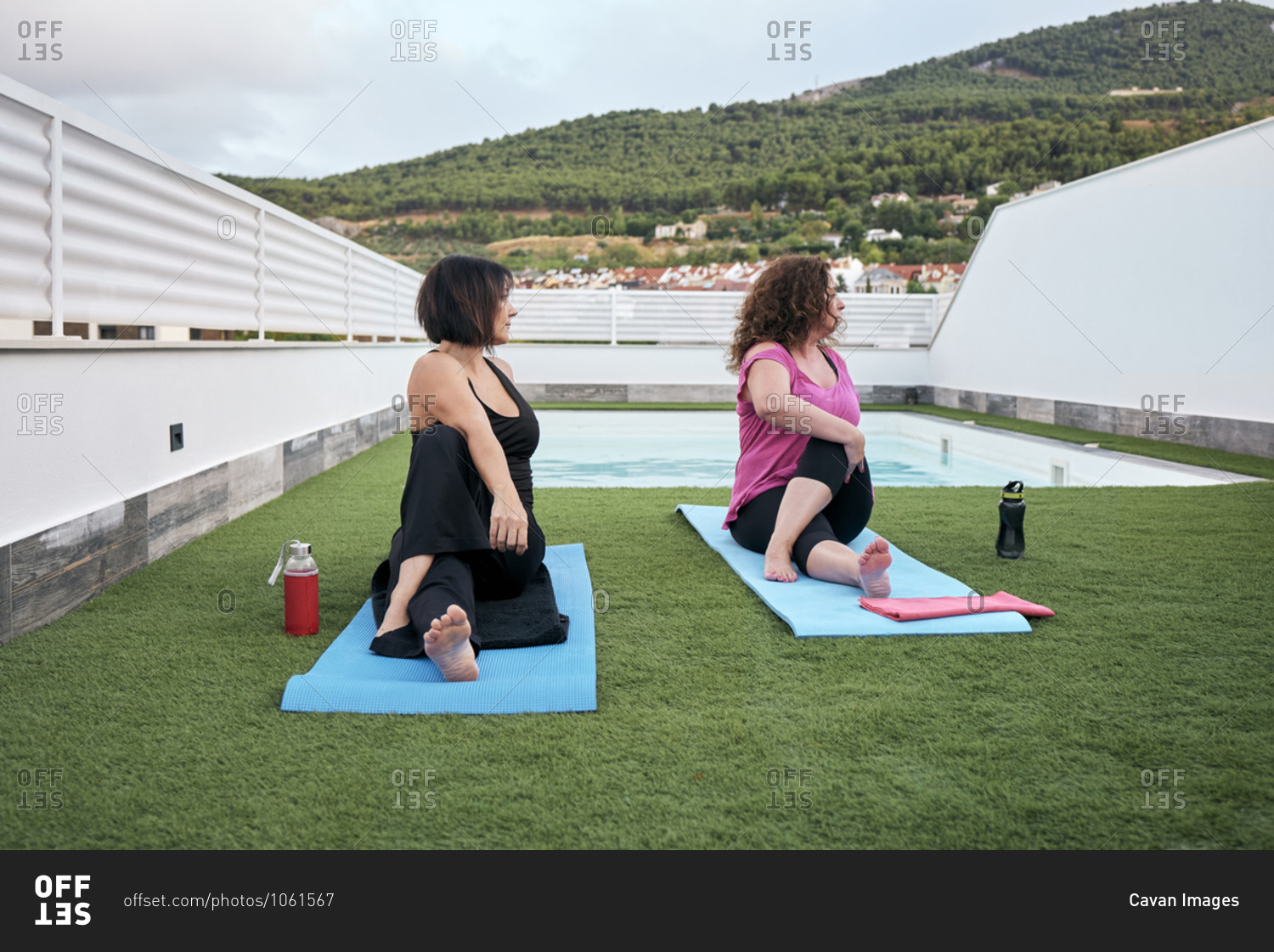 Two women practice yoga on the terrace of the house, Marichi posture