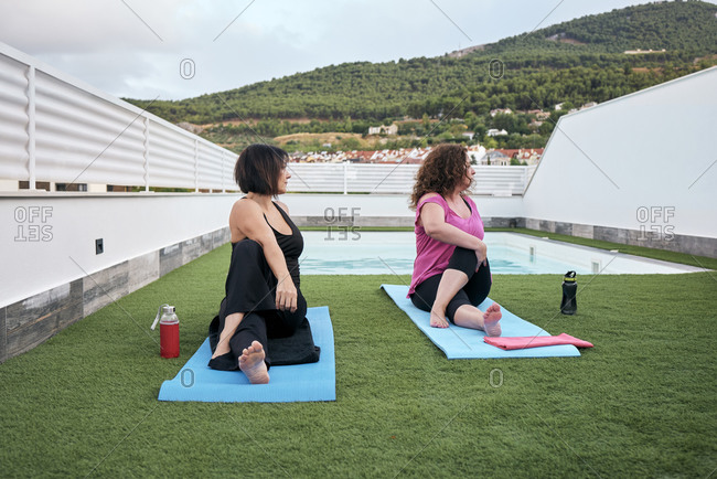 Two women practice yoga on the terrace of the house, Marichi posture