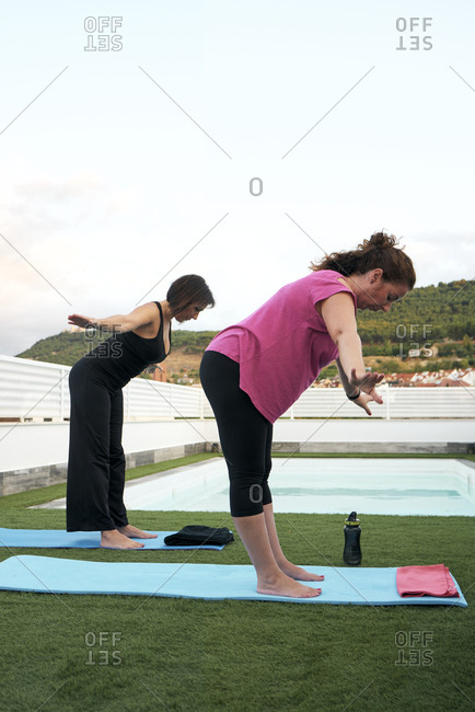 Two women practice yoga on the terrace of the open-air house