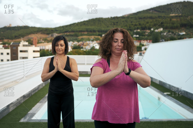 Women do yoga on the terrace of the house, namaste greeting