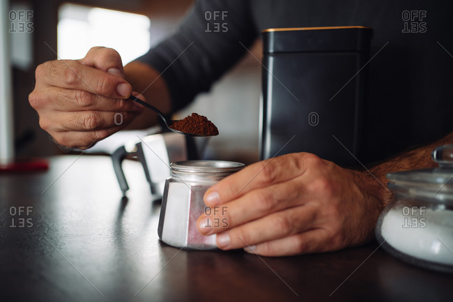 Detail of a person filling an italian coffee maker at the kitchen bar