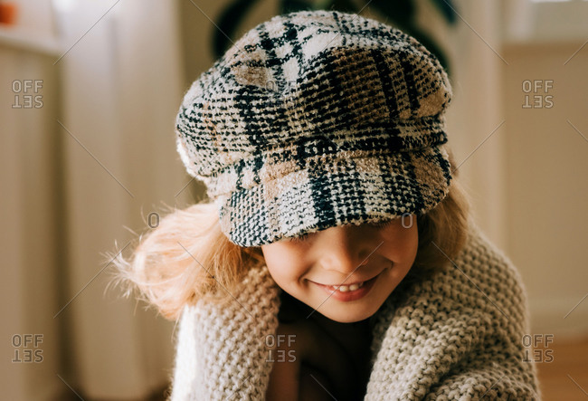 Portrait of a young girl with a hat on playfully smiling at home