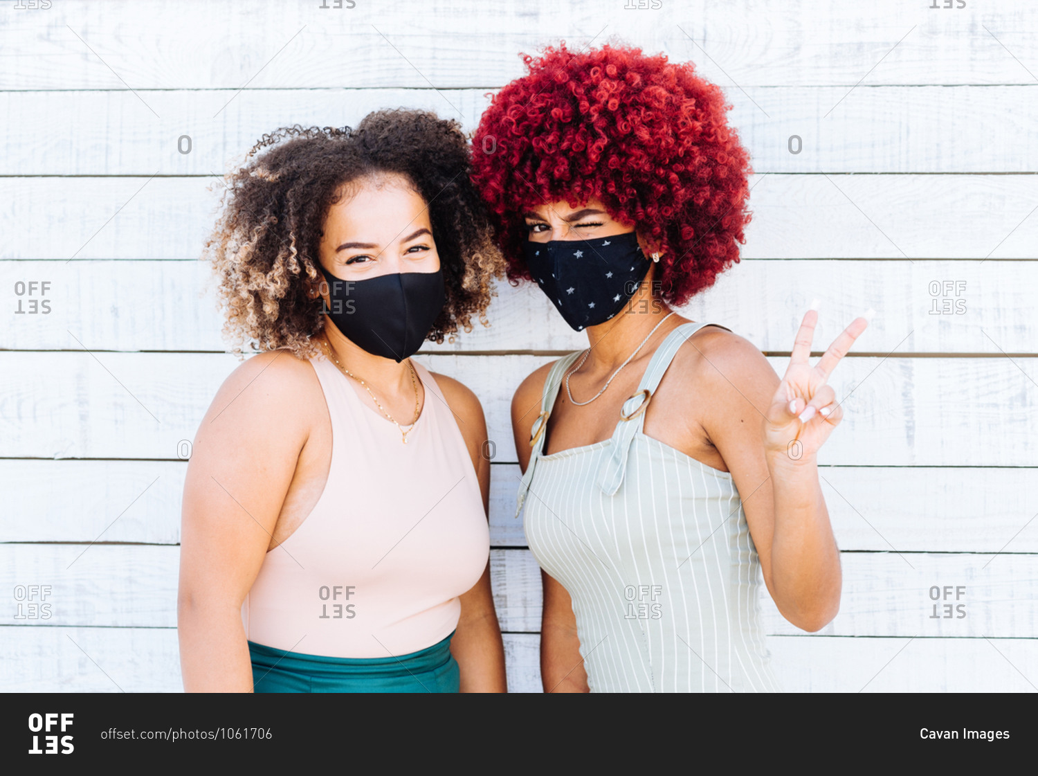 Two latin women with protection mask showing a victory symbol.