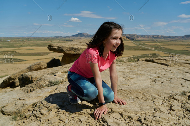 Girl wearing a pink blouse lying on a rock in the Bardenas Reales National Park in Navarra, Spain. Tourism concept