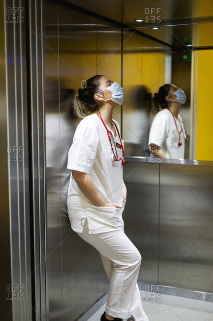 Tired female doctor standing in lift
