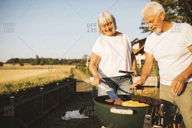 Couple preparing food on grill in garden