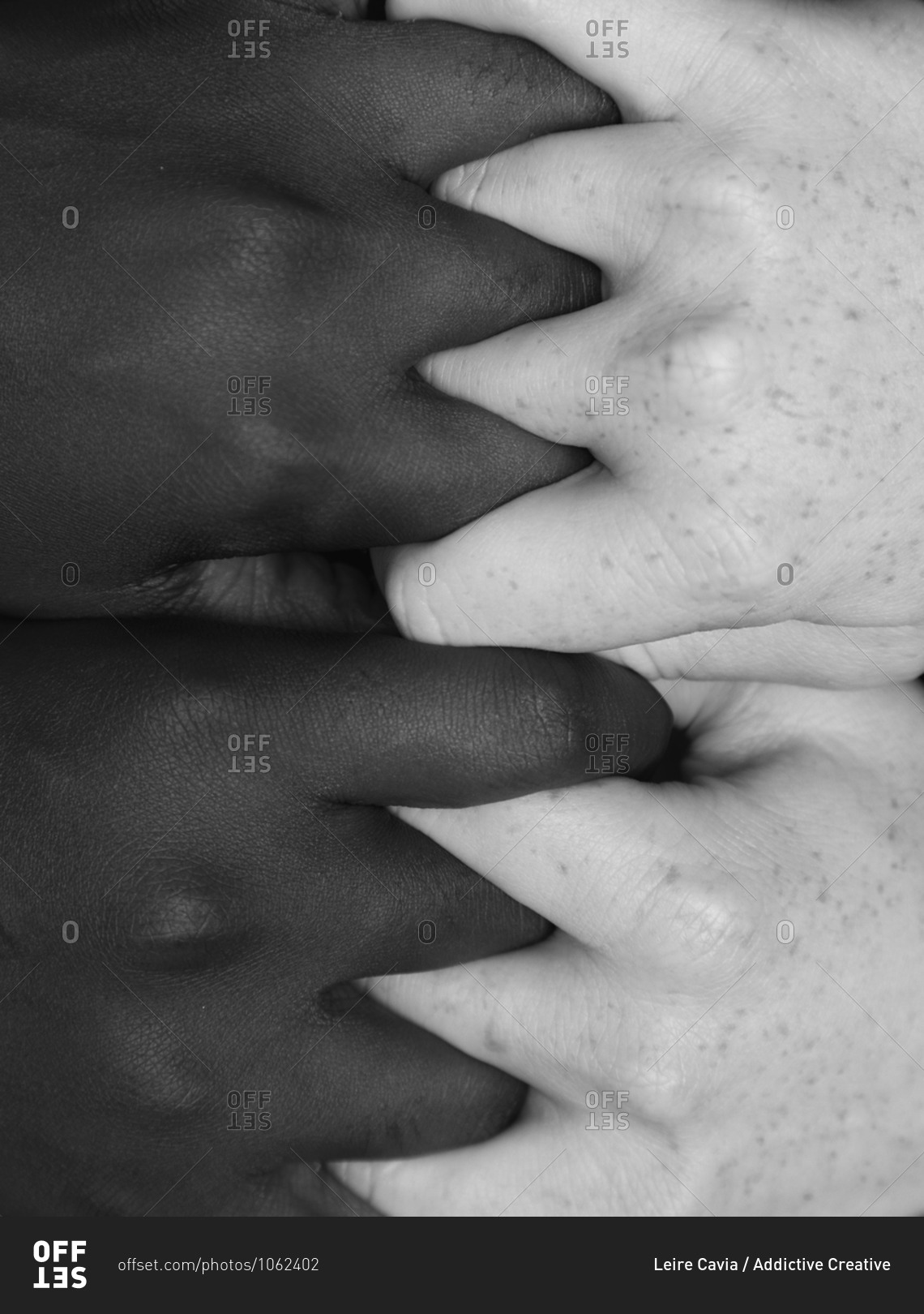 Top view of crop anonymous multiracial females tightly holding hands on black background in studio demonstrating concept of racial equality