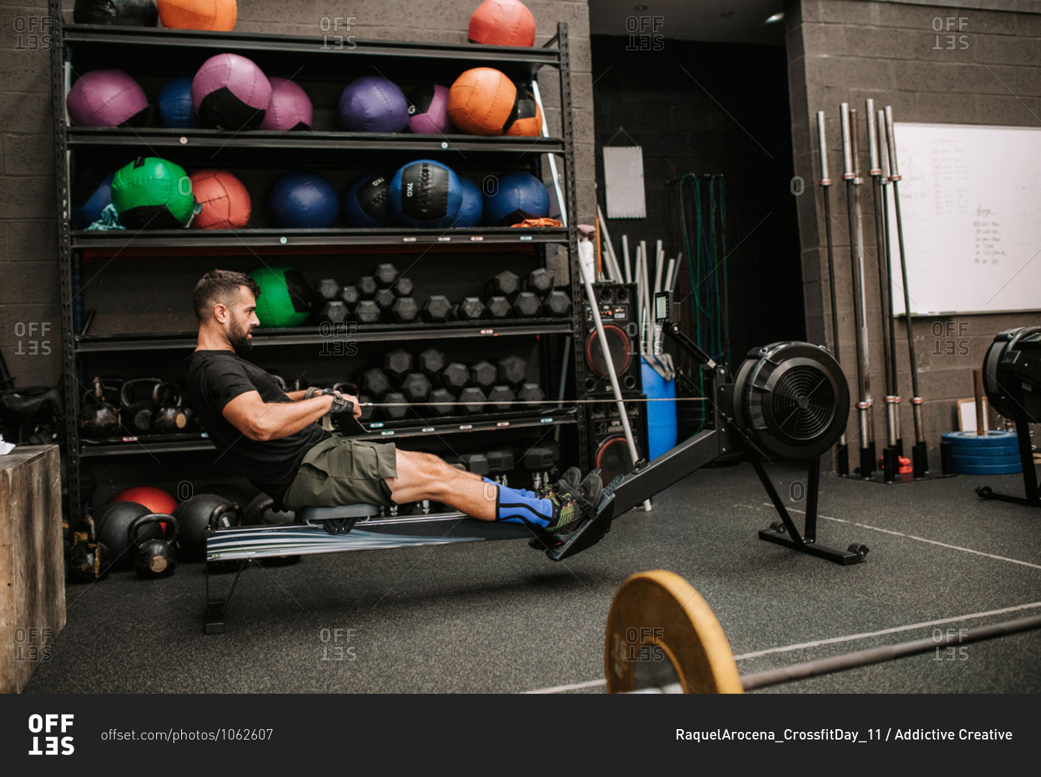 Side view of athletic male with strong body doing exercises on rowing machine in modern sports club