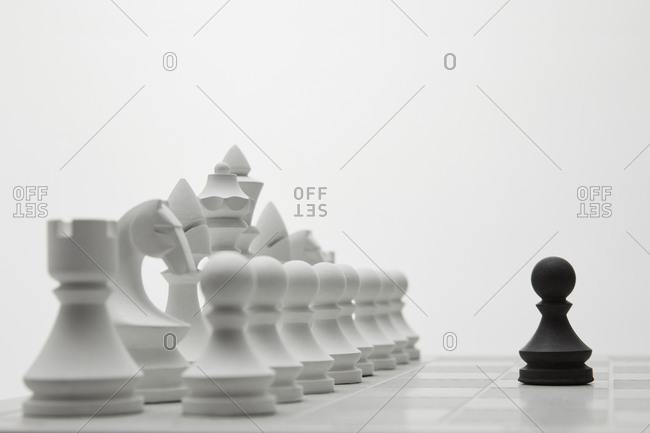 Black pawn figure against rows of white chess.