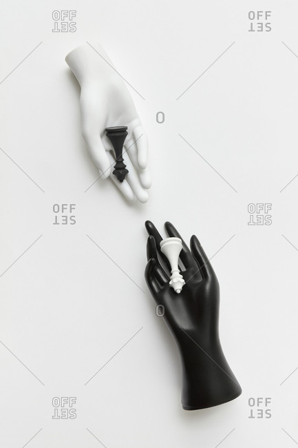 Plastic doll hands with white and black queen figures.