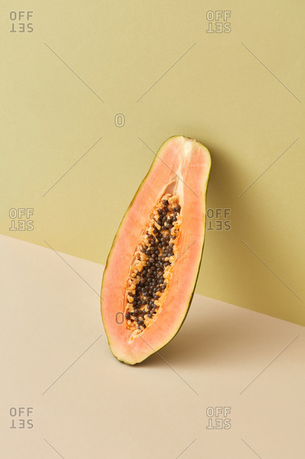 Half of fresh organic papaya fruit leaning on a wall.