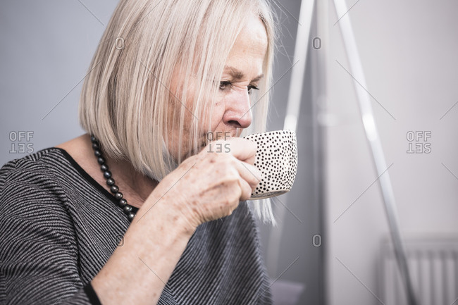 Elderly woman sipping tea from her retirement home