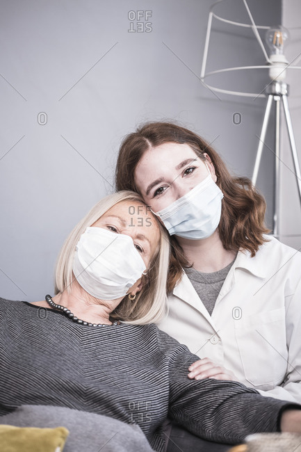 A female healthcare worker comforting an elderly woman who is alone during the pandemic