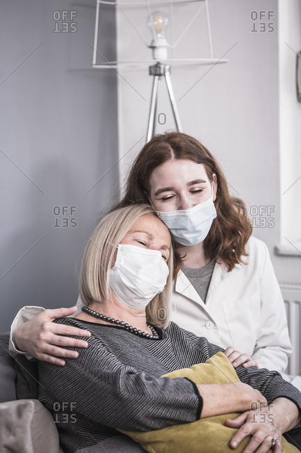 Young female healthcare worker comforting an elderly woman who is alone during the pandemic