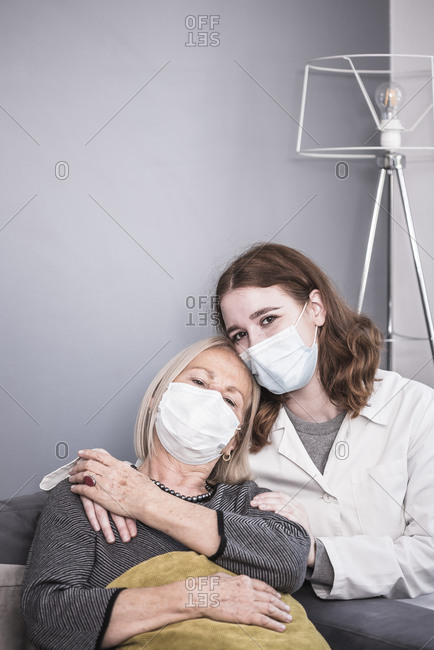 Young healthcare worker comforts an elderly woman who is alone during the coronavirus pandemic