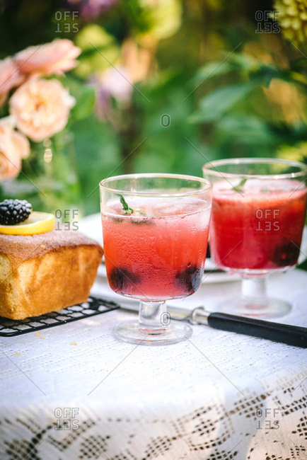 Cake topped with blackberries and lemon on a garden table with peonies
