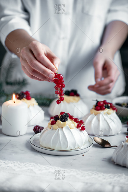 Baker topping a mini pavlova with berries and currants