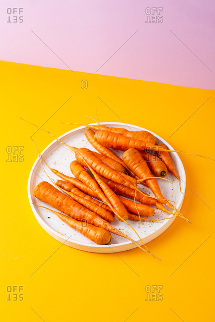 Overhead view of small carrots on white platter