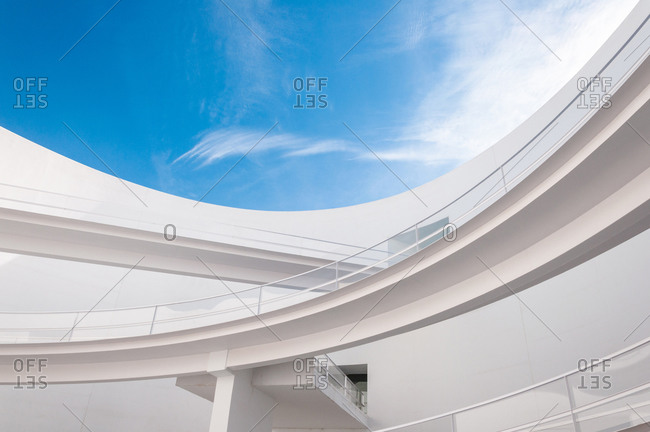 Low angle white minimalist building wall in futuristic style with narrow inclined ramp located under blue sky